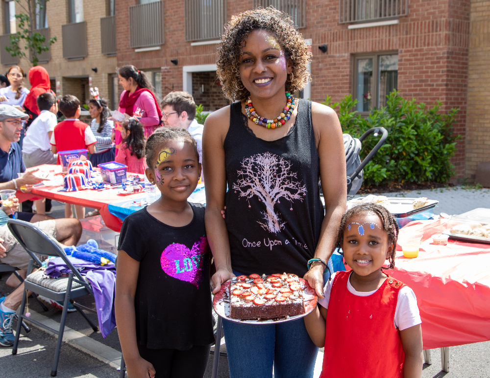A woman poses with a cake and two young girls
