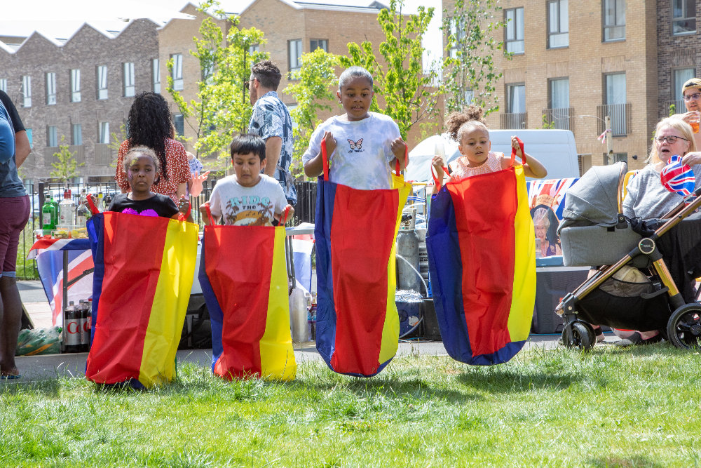 Four children jump in coloured sacks in a race